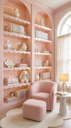 Pink girls reading room with arched built-in bookshelves, scalloped shelf edges, a pink boucle armchair and ottoman and a cloud rug